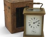 une petite horloge posée à côté d'une boîte sur une surface blanche