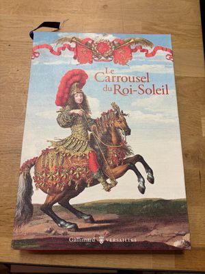 le livre est posé sur une table en bois, avec un chapeau rouge dessus