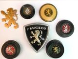 une photo montrant une collection d'emblèmes de voitures sur une surface blanche
