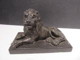 bronze statue of a lion on a base on a white table