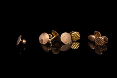 trois paires de boutons de manchette en or sur un fond noir