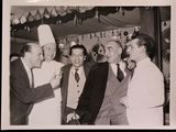 several men in suits and ties standing around a man in a chef ' s hat