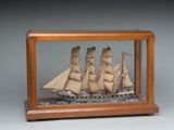 une petite maquette de bateau en bois exposée dans une vitrine