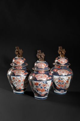 three vases with lids and a bird on top of them
