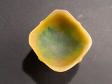 a small yellow bowl on a table with a black background