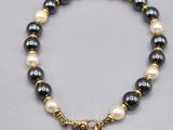 un bracelet de perles noires et blanches avec un fermoir en or