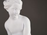 a white statue of a woman sitting on a table