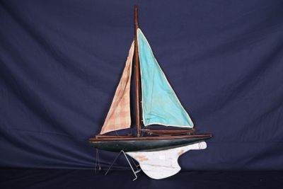 un petit voilier en bois posé sur un socle, devant un fond bleu
