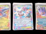 trois cartes Pokémon différentes dans des pochettes en plastique, sur fond noir