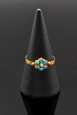 une bague en or sertie de turquoises sur un cône noir