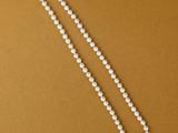 a close up of a white pearl necklace on a brown background