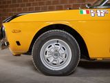 a yellow car parked in front of a brick wall
