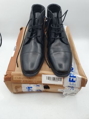 une paire de chaussures en cuir noir posée sur une boîte en carton
