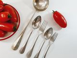 a bowl of tomatoes and spoons next to a bowl of tomatoes