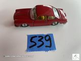 une petite voiture rouge posée à côté d'un autocollant bleu portant le numéro 539