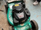 a green lawn mower that is sitting on the ground