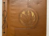 un vieux livre en cuir marron dont la couverture est ornée d'un motif de feuilles