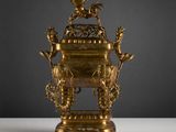 une urne ancienne en laiton posée sur une table blanche, sur fond noir