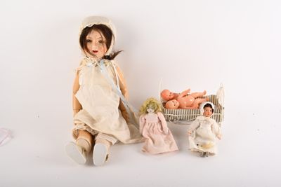 une poupée assise à côté d'un panier rempli de poupées et d'un panier rempli d'œufs