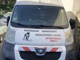une camionnette blanche garée à côté d'un immeuble sur lequel est accrochée une pancarte