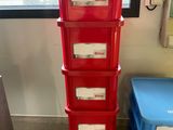une pile de récipients en plastique rouges et bleus devant une fenêtre