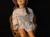 a doll that is sitting in a chair with a hat on