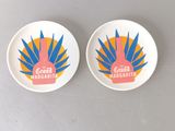 two plates with colorful designs on them sitting on a table