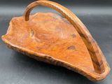 une photo représentant un panier en bois muni d'une anse, posé sur une table
