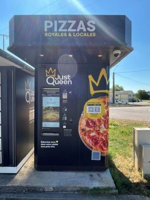 un distributeur automatique sur lequel est posée une pizza
