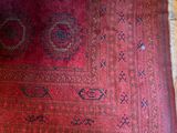 une photo d'un tapis rouge posé sur un parquet, près d'une fenêtre