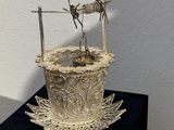 a metal sculpture of a bird on top of a flower pot