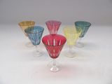 quatre verres à pied de couleurs différentes posés sur une table blanche