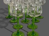 six green wine glasses are lined up in a row on a gray surface