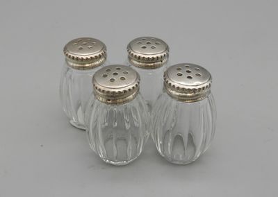 trois salières et poivrières en verre posées sur une surface blanche