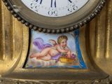 a gold clock with a picture of a cupid on it