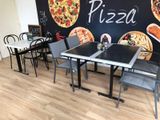 tables and chairs in a restaurant with a pizza mural on the wall