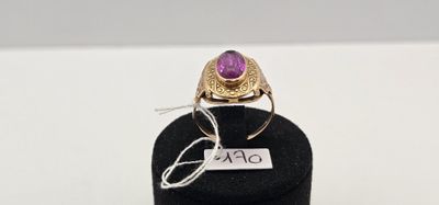 une image représentant une bague ornée d'une pierre violette posée sur un support noir