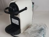 a white coffee machine sitting on a table with a plastic bag