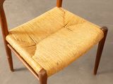 a wooden chair with a woven seat on a concrete floor