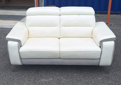 un canapé en cuir blanc posé devant un conteneur bleu