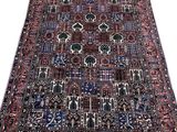 un tapis persan ancien aux couleurs bleues, rouges et noires