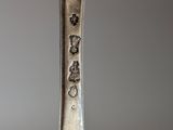 an old silver spoon with chinese writing on it sitting on a table