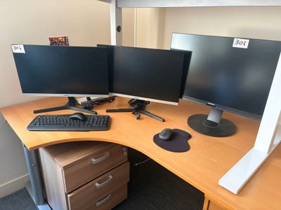 a desk with two monitors and a keyboard on it