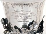 a silver vase sitting on a table with a label on it