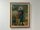 un tableau représentant une femme avec un panier de fleurs accroché au mur