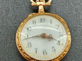 une montre de poche en or au cadran blanc posée sur une table