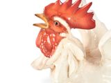 rooster figurine on a white background next to a pile of coins