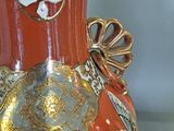 a red vase with gold decorations on it on a table