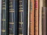 several old books are lined up in a row on a shelf