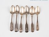 six silver spoons are lined up in a row on a white surface